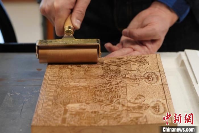 圖為徐晉林工作室工作人員正在給雕好壁畫的版面滾油墨?！【琶赖┰?　攝