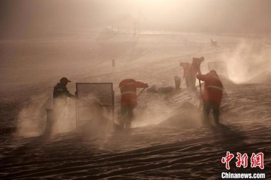 圖為敦煌市鳴沙山月牙泉景區(qū)“駱駝保姆”清理駱駝糞便?！垥粤?攝