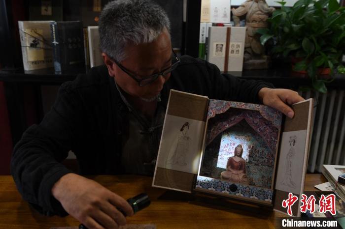 圖為讀者出版集團(tuán)讀者晉林工作室獨(dú)立出品人徐晉林，展示互動(dòng)性強(qiáng)的敦煌題材手工書。(資料圖) 楊艷敏 攝