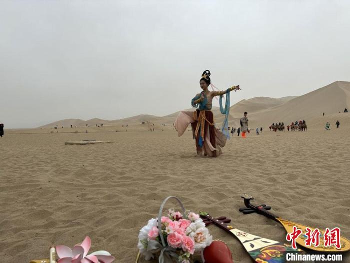 圖為2023年4月底，敦煌大漠“逐舞者”奧楠在鳴沙山月牙泉景區(qū)視頻直播敦煌舞。　馮志軍 攝