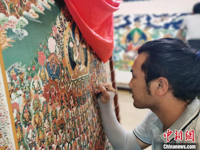 圖為更登才讓的徒弟繪畫唐卡?！?zhí)砀?攝