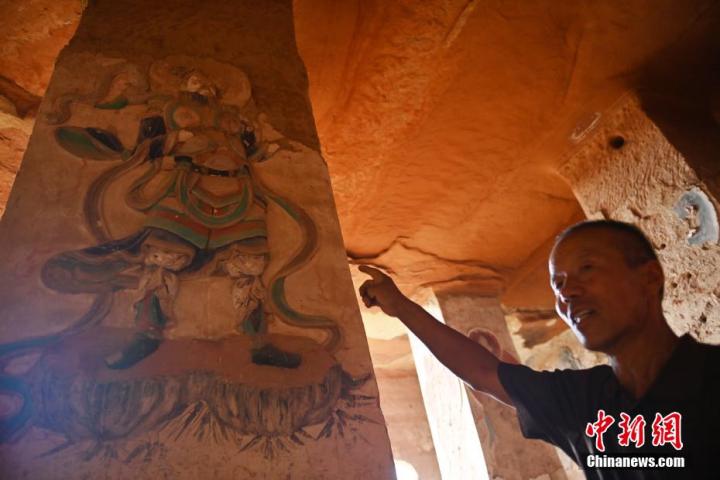 7月15日，甘肅省平?jīng)鍪袥艽h百里石窟長(zhǎng)廊羅漢洞石窟內(nèi)，該窟文保員郭建平介紹窟內(nèi)石刻彩繪壁畫(huà)。郭建平家中三代人曾自發(fā)保護(hù)羅漢洞石窟。羅漢洞石窟遺存40余個(gè)窟龕，以北魏至清代風(fēng)格為主。中新社記者 李亞龍 攝</p>
<p>